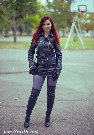 In an autumn park, the redheaded girl named Jeny removes her skirt to pose seductively in her seamless blue pantyhose, wearing only a leather jacket and high boots